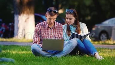 一男一女的朋友坐在公园的草地上，享受着笔记本电脑。 在背景下，人们走路